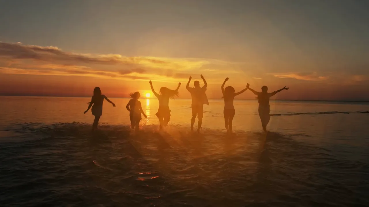 A group of friends jumping in the sea at sunset